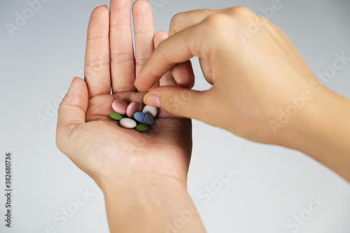 Woman taking a pill.Colorful pills in woman's handful on white background.