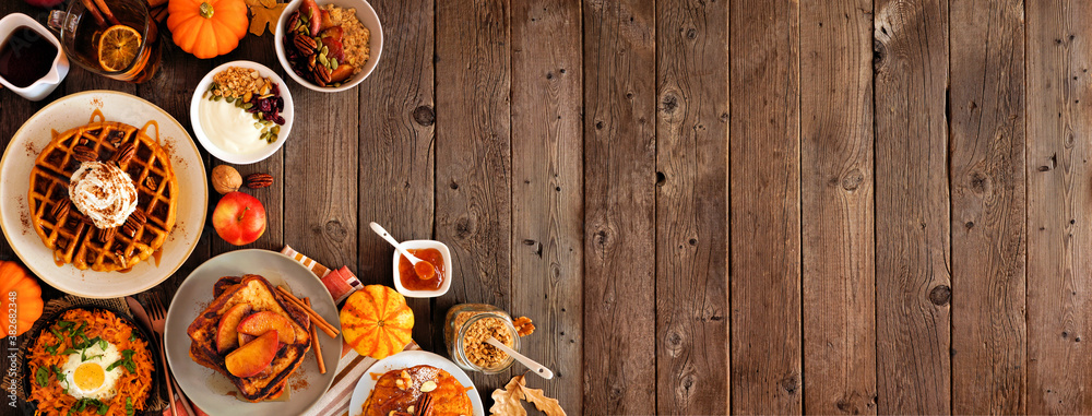Variety of autumn breakfast or brunch items. Corner border against a dark wood banner background. Pumpkin spice waffles, apple french toast, oatmeal, egg skillet, yogurt. Top view. Copy space. Variety of autumn breakfast or brunch items. Corner border against a dark wood banner background. Pumpkin spice waffles, apple french toast, oatmeal, egg skillet, yogurt. Top view. Copy space.