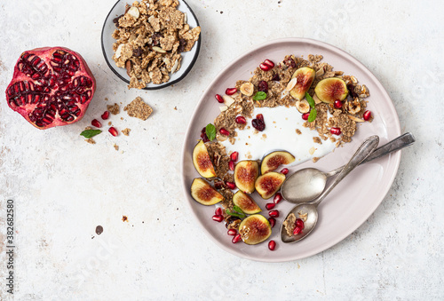 Bowl of greek yogurt with granola , fresh fig and pomegranate seeds