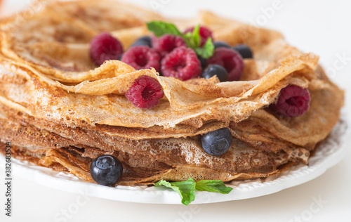 Tasty homemade crepes with berries and honey.  Pancakes with berries