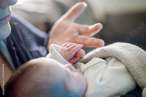 Young Mother and her Baby Newborn Love Emotional Family - Close-up of Baby sleeping in bed with hand of mother - Mother with her newborn baby care hands