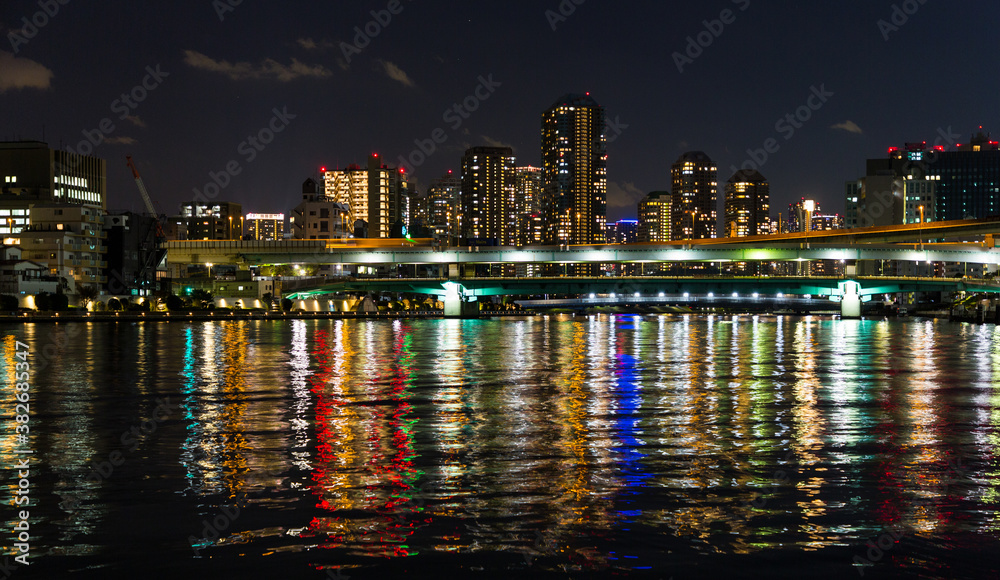 Fototapeta premium Dark skyline of Tokyo city at night with illuminated buildings, low horizon, empty space for caption.