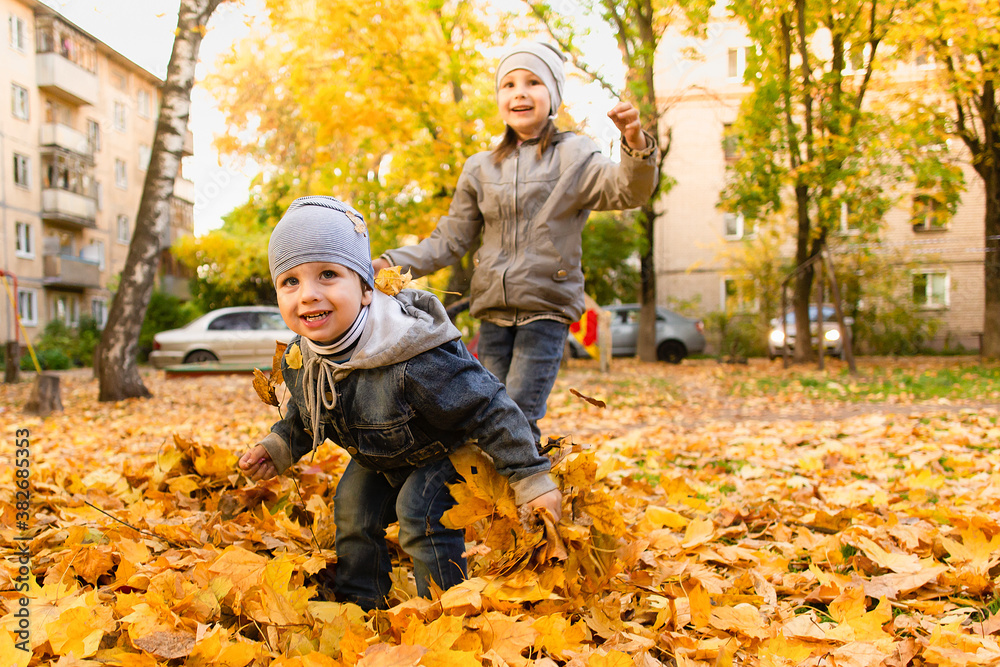 Happy boy and girl play in autumn foliage Happy boy and girl play in autumn foliage