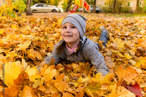 Girl plays in autumn foliage