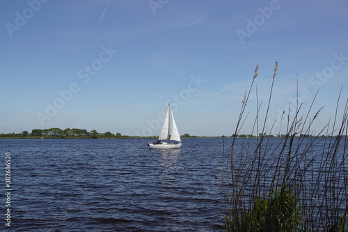 View on the Alkmaardermeer lake with a sailing ship near the Dutch village of Akersloot. Netherlands, May 