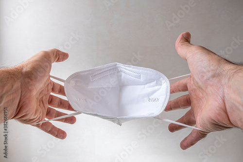 hands holding a mask KN95 FPP2 of protection against COVID-19 to be placed on the face photo