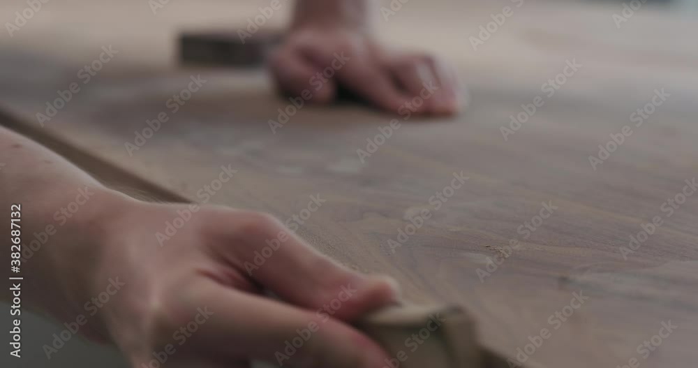 Slow motion slide orbit shot of man hand sanding black walnut wood table Slow motion slide orbit shot of man hand sanding black walnut wood table