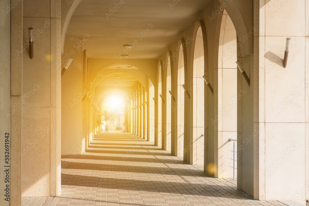 Obraz premium Passage with columns in perspective to the glare of the sun. Lead to success in the light.