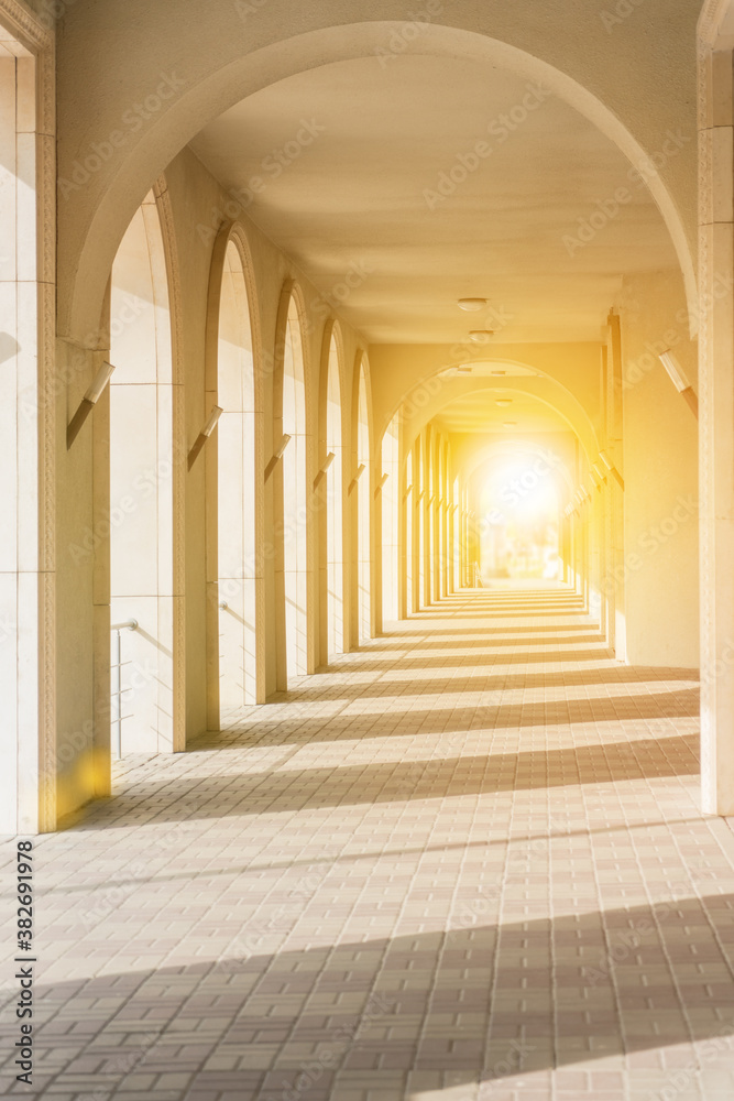 Passage with columns in perspective to the glare of the sun. Lead to success in the light.