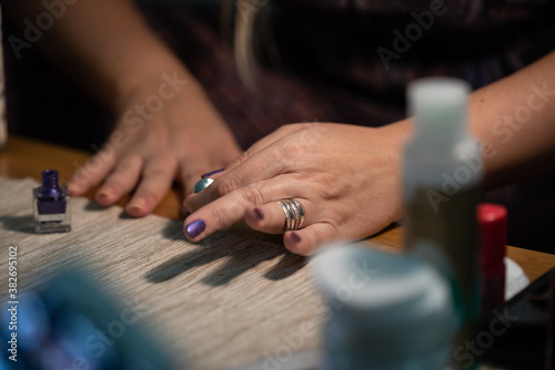 The woman is painting her nails purple, close up