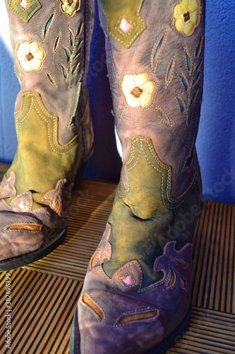 Women's cowboy boots with flower design on a wooden plank floor