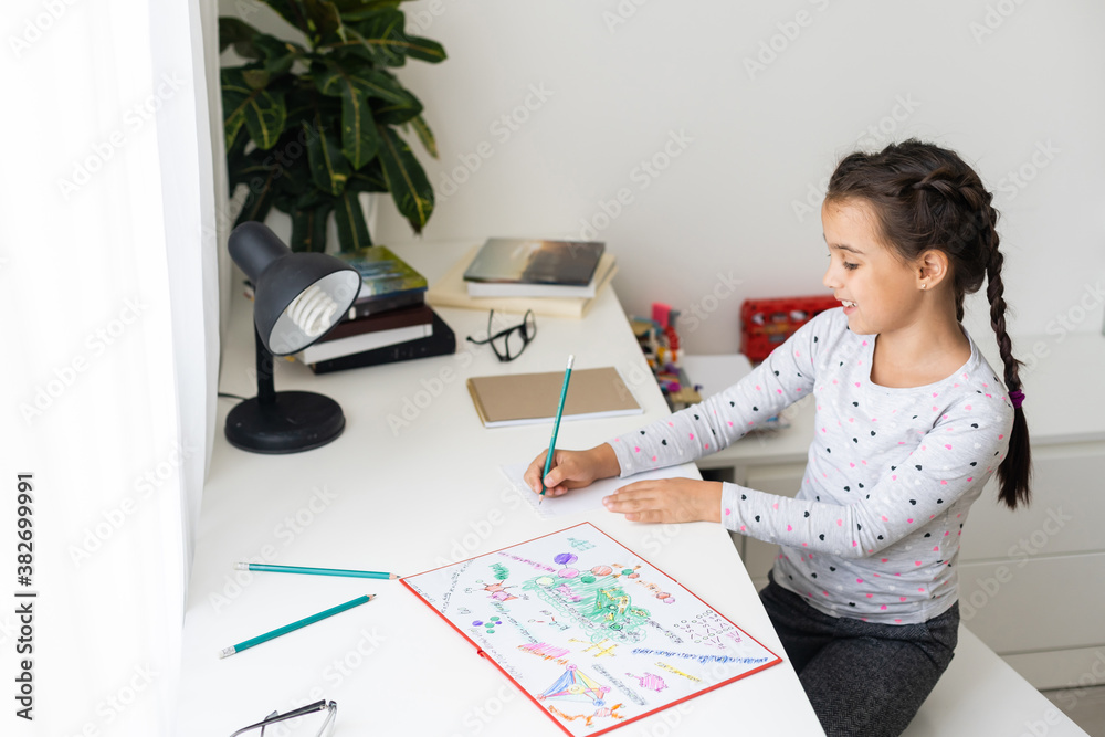 cute happy little girl writing something in her notebook