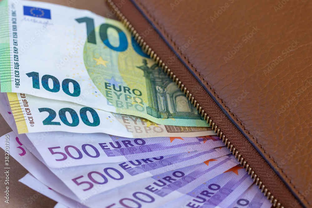 Obraz premium 100, 200, 500 euro banknotes under a brown wallet, closeup