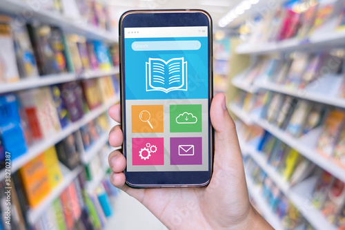 Man hand holding mobile smart phone , tablet,cellphone over Blur Shop Background in Book store Shelf Natural bokeh out of focus Bookstore,Blur background of people in library,book store.vintage photo