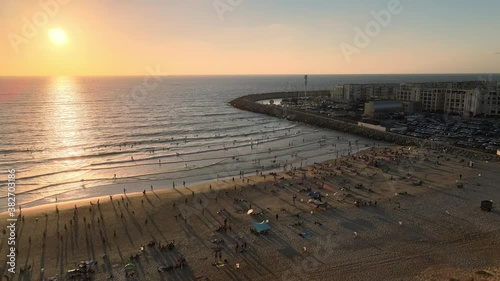 Sunset over Herzlia's Marina. People on the beach. Aerial 4K Shot. Herzlia, Israel.