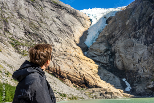 Sichtbarer Klimawandel: Junger Mann betrachtet den sich zurückzieheneden Gletscher "Briksdalsbre" Nähe Olden