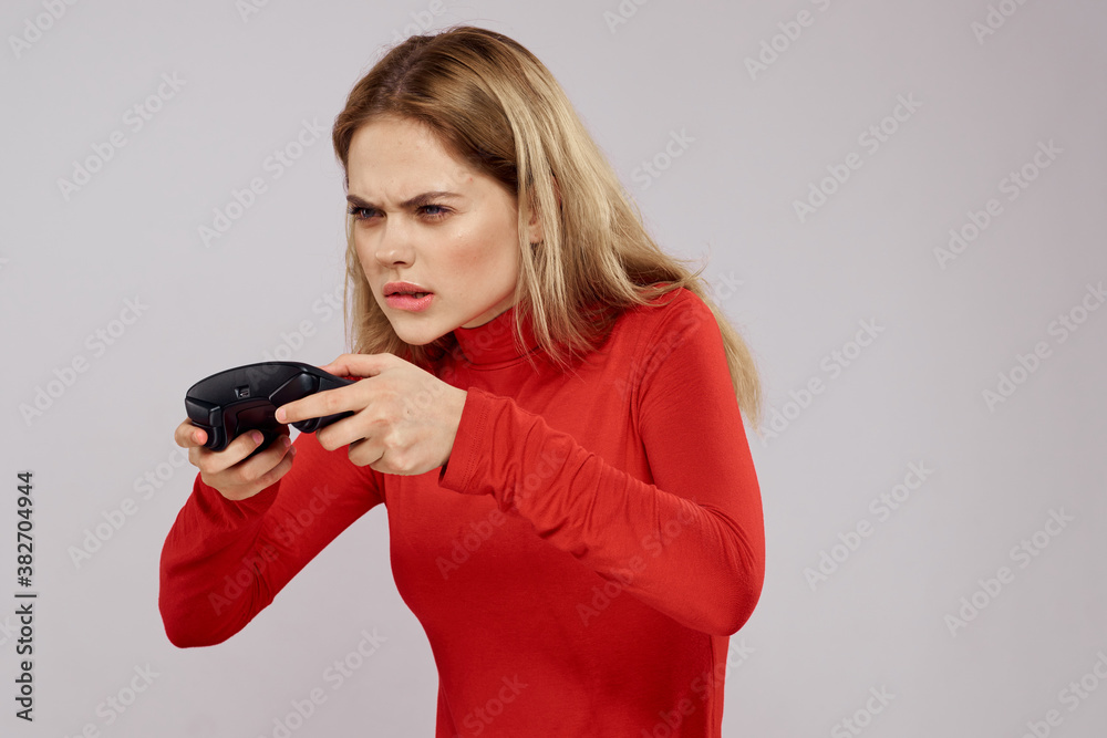 Woman with gamepad in hands playing games emotions lifestyle leisure red shirt light background Woman with gamepad in hands playing games emotions lifestyle leisure red shirt light background