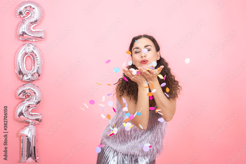 Young woman on a pink background with silver ballons in the form of the numbers 2021 Young woman on a pink background with silver ballons in the form of the numbers 2021