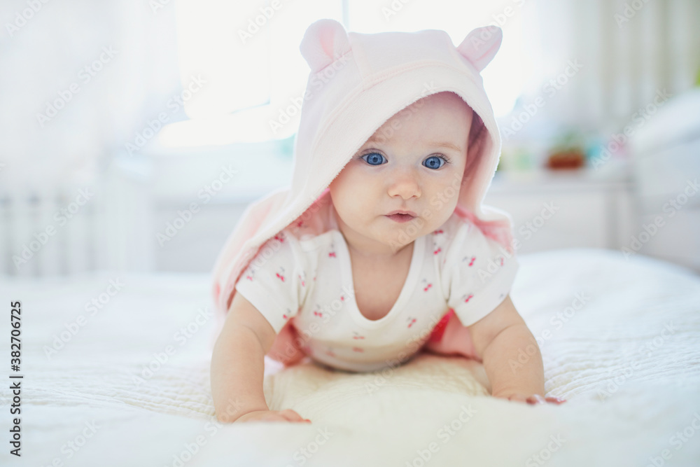 baby girl relaxing in bedroom in pink clothes or towel with ears baby girl relaxing in bedroom in pink clothes or towel with ears