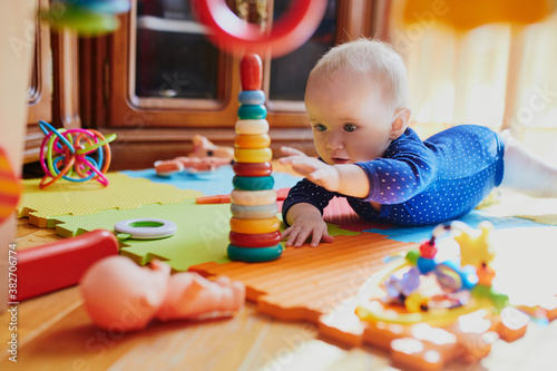 Obraz na plátně Baby girl playing with toys on the floor