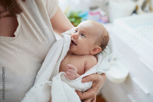 Foto Mother holding baby wrapped in towel after bath