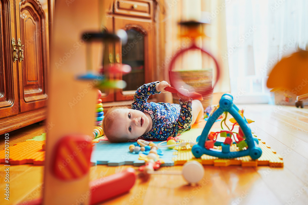 Naklejka premium Baby girl playing with toys on the floor