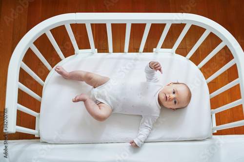 Baby girl in co-sleeper attached to parents' bed photo