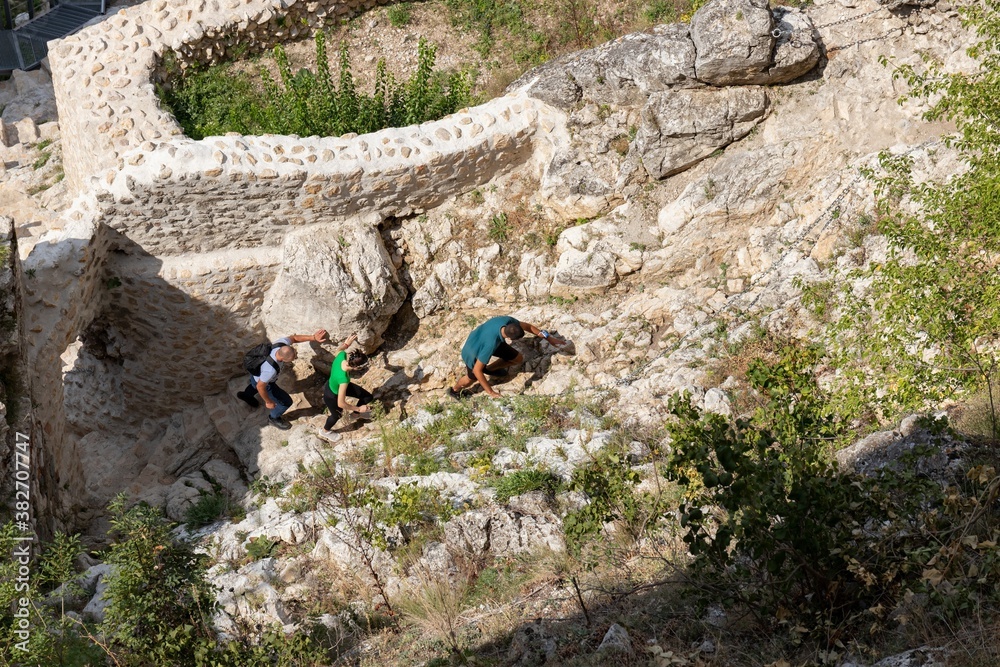 Three tourists climb the stone road in the territory of the old fortress, top view Three tourists climb the stone road in the territory of the old fortress, top view