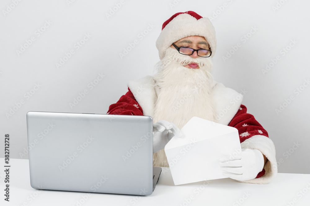 Santa Claus is sitting at his desk and reading letters. Santa Claus is sitting at his desk and reading letters.