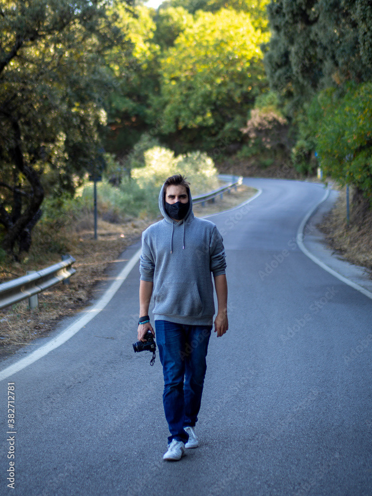 Obraz premium Hombre caminando por una carretera usando mascarilla