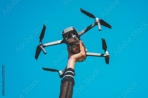 Woman hand holding drone or quadcopter isolated on the blue sky background.