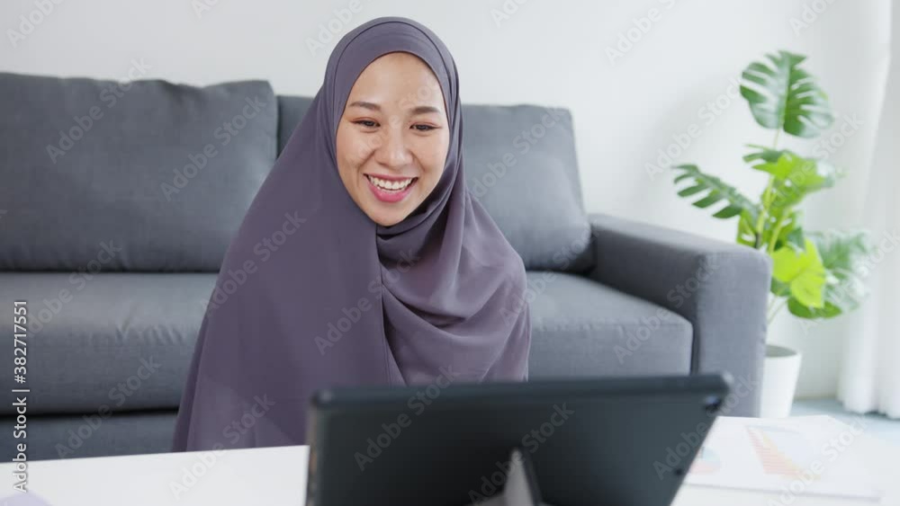 Asia muslim lady wear headscarf casual use tablet talk to colleagues about sale report in conference video call while working from home at living room. Social distancing, quarantine for corona virus. Asia muslim lady wear headscarf casual use tablet talk to colleagues about sale report in conference video call while working from home at living room. Social distancing, quarantine for corona virus.