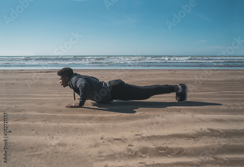 Athletic man doing push-ups at the beach.