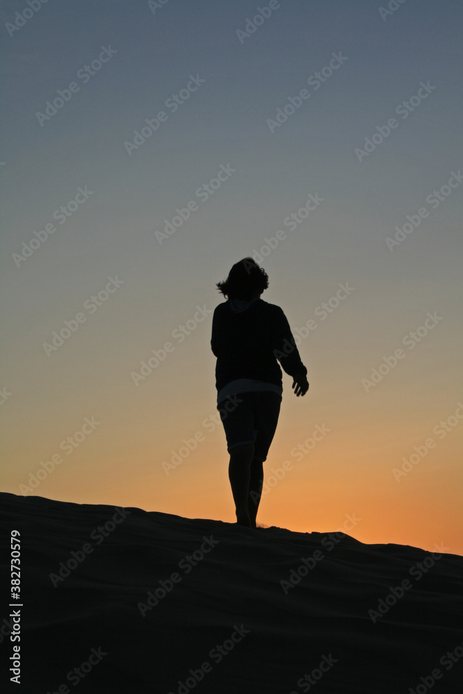 Silhouette of a child at sunset on a dune