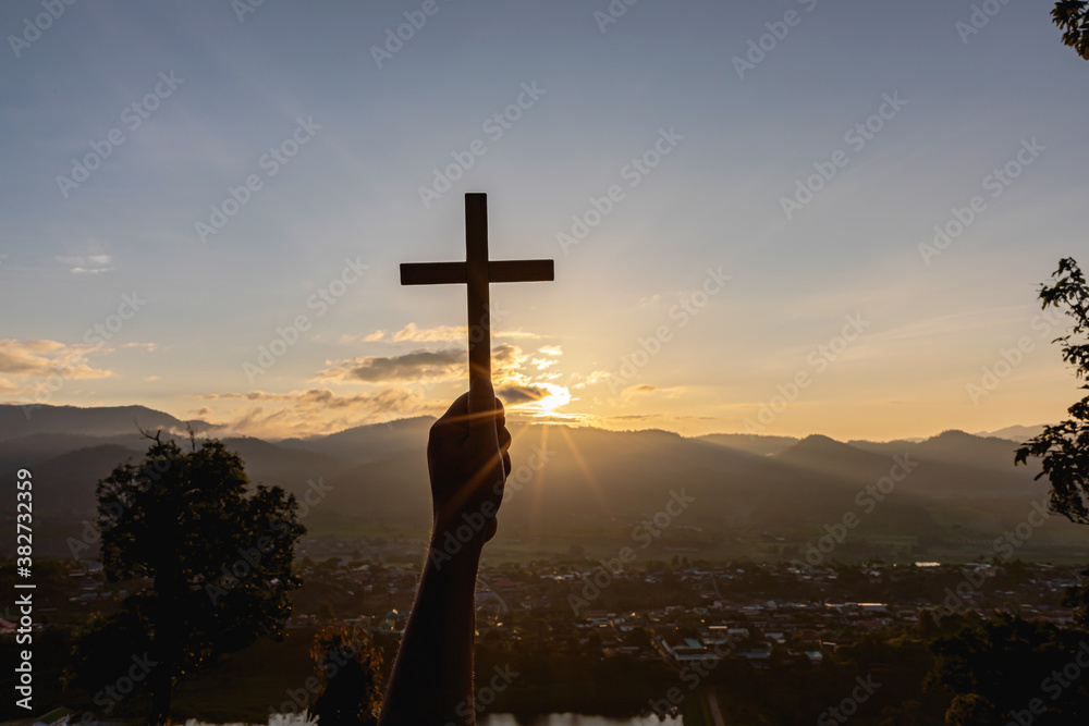 Christian, Christianity, Religion copy space background. Human praying and holding christian cross for worshipping God at sunset background.silhouette