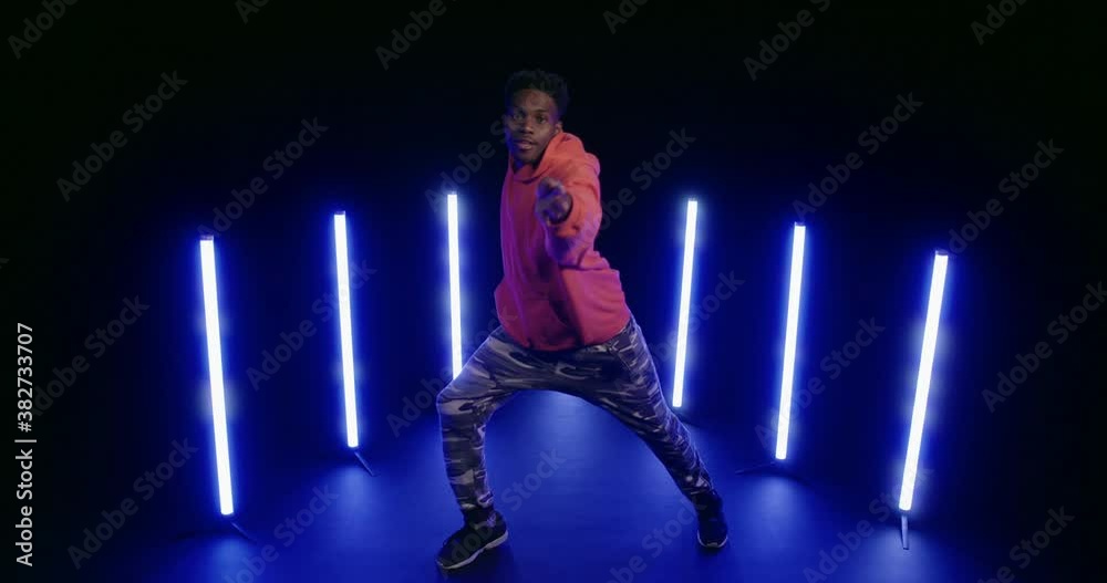 Studio, slow motion, young man dances backlit by ultraviolet light Studio, slow motion, young man dances backlit by ultraviolet light
