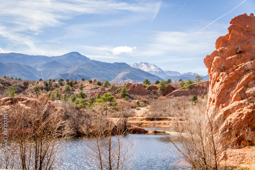 red rock formation with lake and mountains and sky