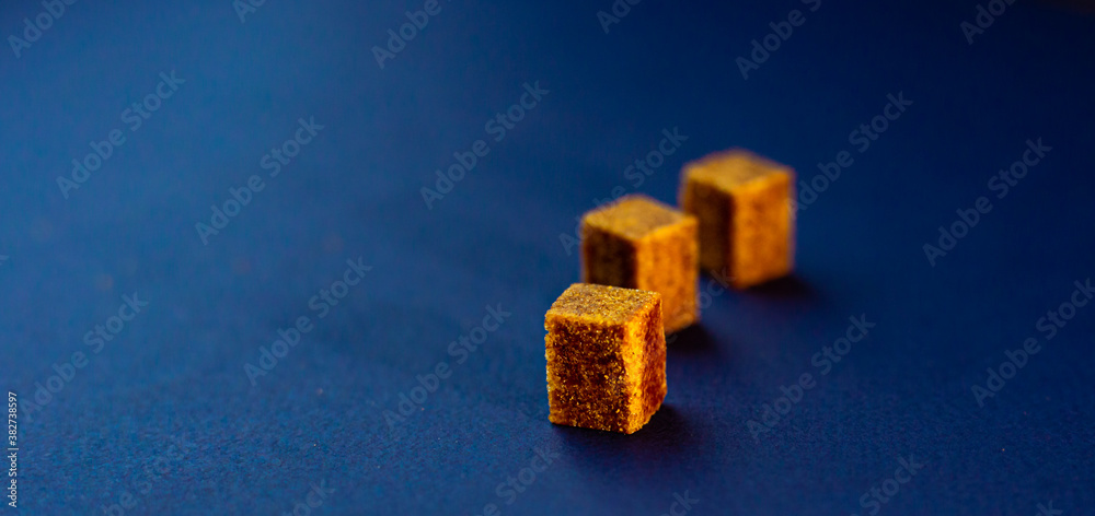 Brown sugar cubes on blue background. Diagrams concept. Brown sugar cubes on blue background. Diagrams concept.