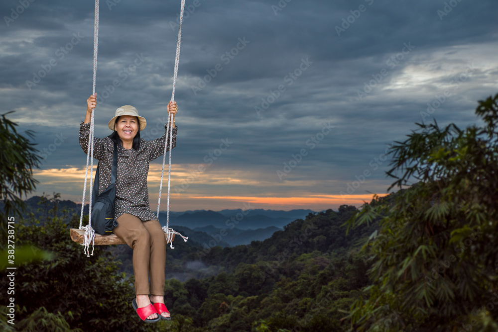 Retired woman Happy on the swing At the viewpoint on the mountain at sunset Retired woman Happy on the swing At the viewpoint on the mountain at sunset