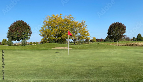 early autumn golf course green red flag leaves changing treetops 