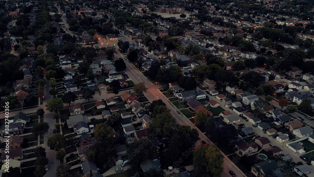 Aerial drone view of suburban neighborhood at  dusk. Establishing shot of American  suburb. Residential houses, night street