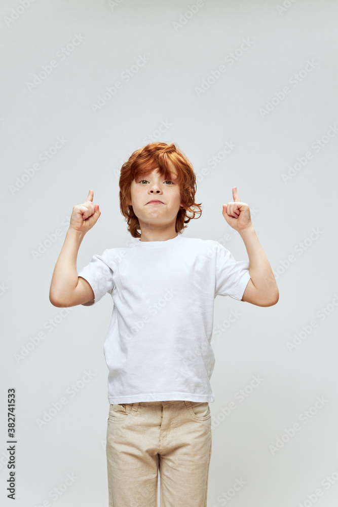 Portrait of a red-haired boy gesturing with his hands showing upward white t-shirt Copy Space Portrait of a red-haired boy gesturing with his hands showing upward white t-shirt Copy Space