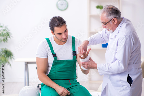 Young male contractor visiting old doctor