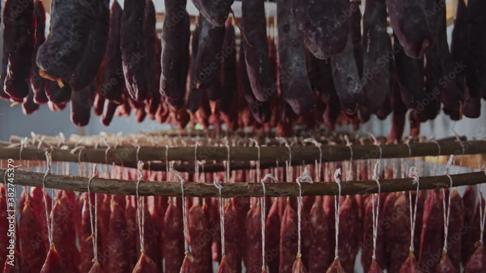 At meat factory in large smokehouse variety of salami and sausage sticks smoked and stored. Meat storage. Sausages production.