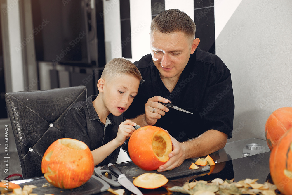 Family in a kitchen. People prepares to halloween. Family cuts pumpkins.