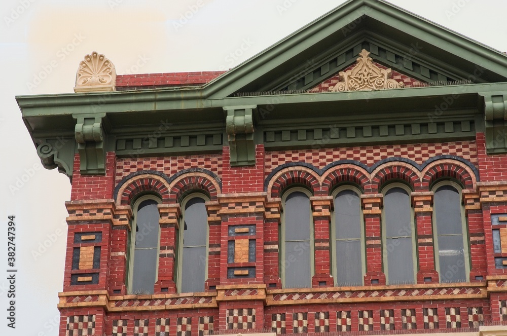 Detail of historic building on Galveston Island, Texas with intricate, colorful brick designs, green roof, and facade