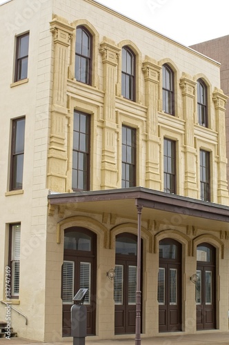 Vertical: Historic stone building in Galveston Island, Texas with tall windows, brown doors, and awning © skyoftexas