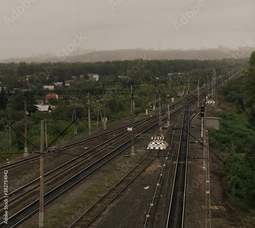 Railroad tracks in cloudy weather against the background of a rainy city