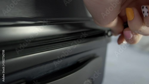 Close up hand of Young Asian travel woman unpacking suitcase by unzipping luggage on bed. photo