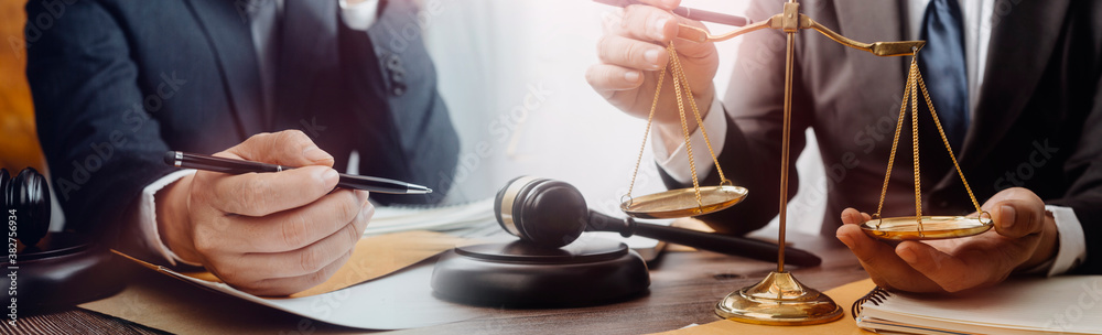 Business and lawyers discussing contract papers with brass scale on desk in office. Law, legal services, advice, justice and law concept picture with film grain effect